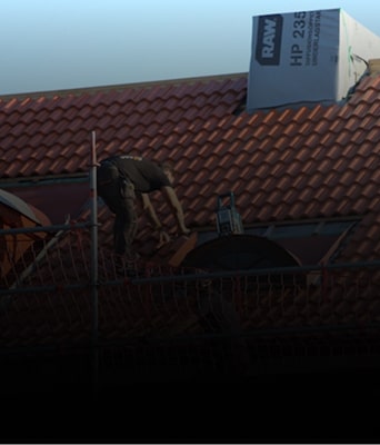 Roofer installing tiles on a red roof.
